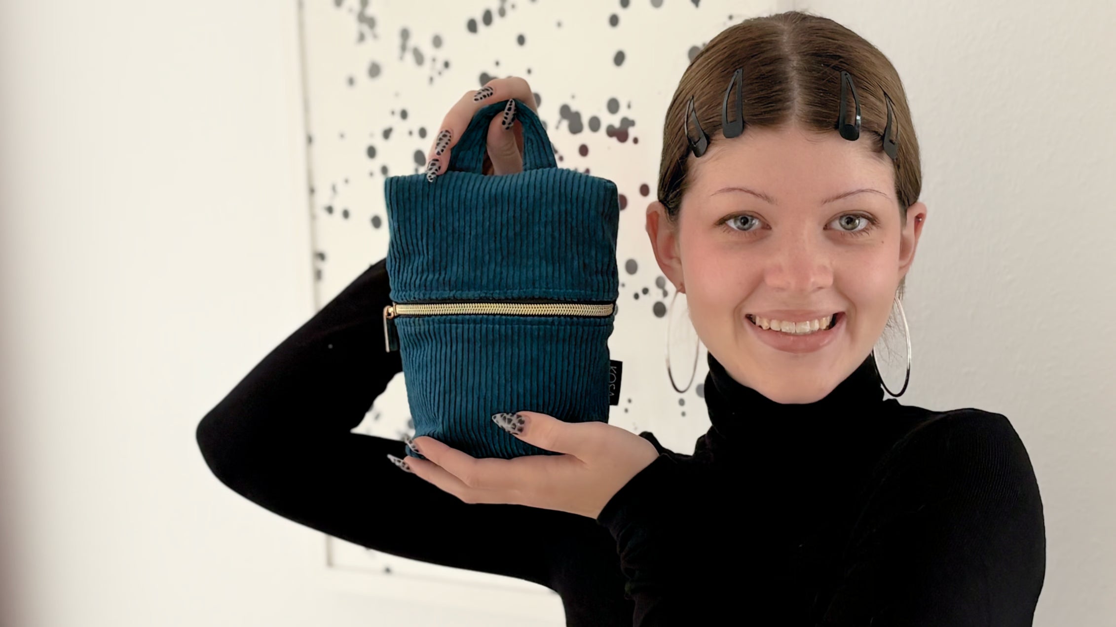 Schöne, stehende Kosmetiktasche, präsentiert von stylischer junger Frau.
Beautiful, upright cosmetic bag, presented by a stylish young woman